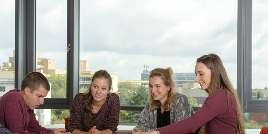Studierende am Tisch Eine Gruppe Studierender sitzt mit Lernunterlagen am Tisch.