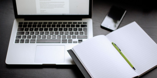 Laptop, Notizbuch und Smartphone Laptop, Smartphone und Notizbuch mit Stift auf einem Tisch liegend.