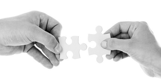 Hands connecting a piece of a puzzle